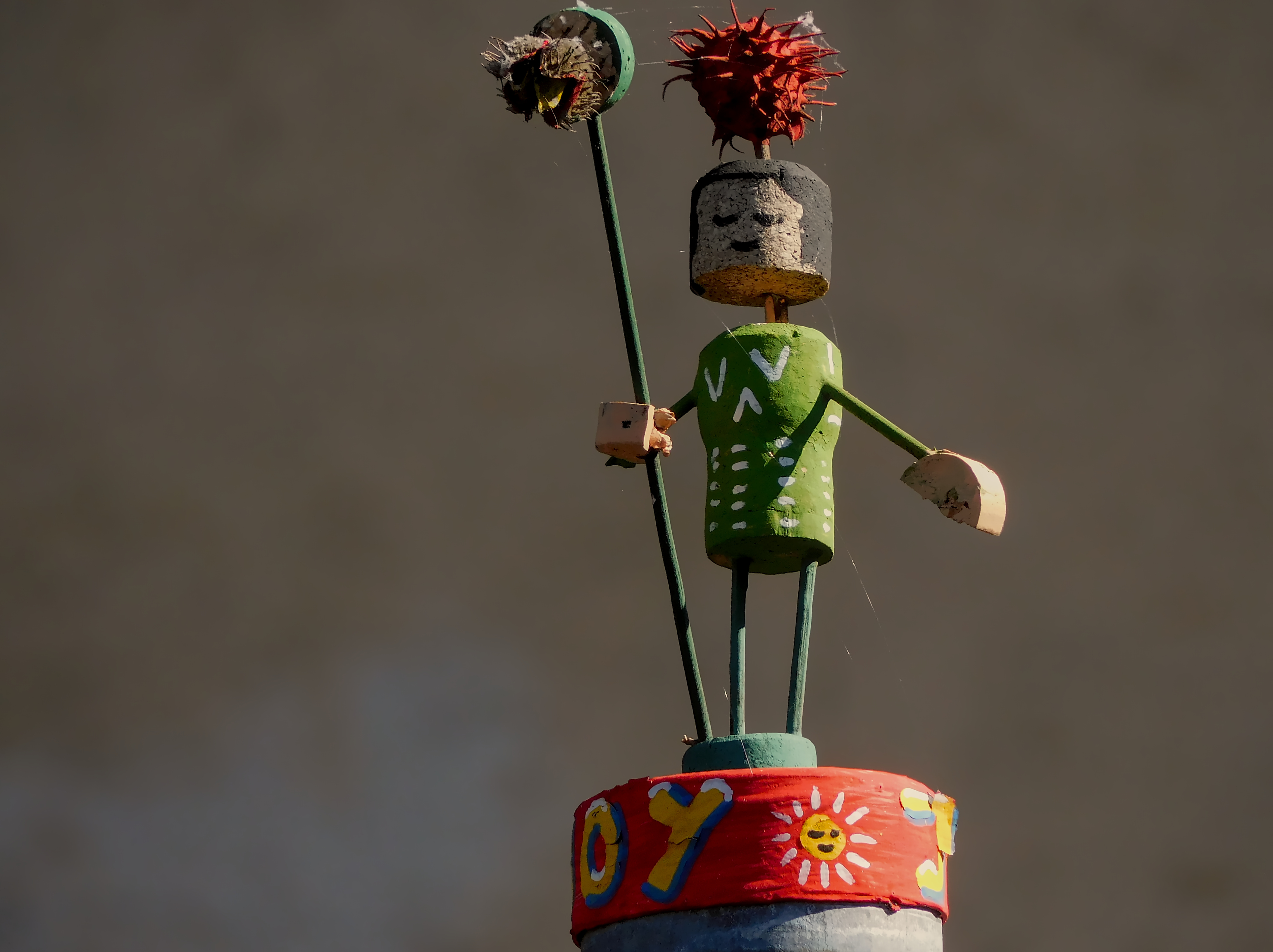 A painted cork-man on top of a street sign